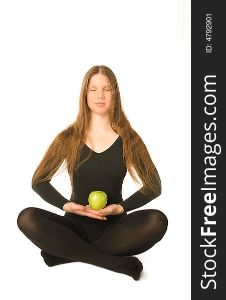 The portrait of a woman in lotus pose with a green apple in her hands. The portrait of a woman in lotus pose with a green apple in her hands