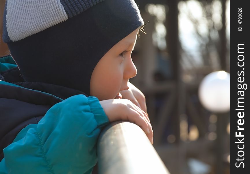 The little boy to stand about a metal handrail on a background of a white lantern. The little boy to stand about a metal handrail on a background of a white lantern