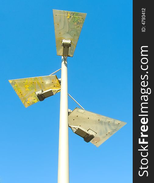 Post with three lamps of unusual construction on a background blue sky