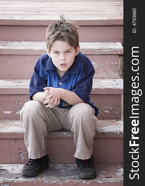 Grumpy Young Boy Sitting on Peeling Stairs. Grumpy Young Boy Sitting on Peeling Stairs