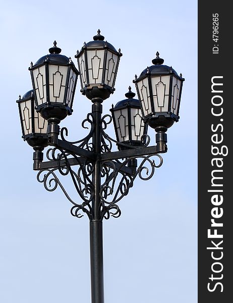 Old black street lamp under blue sky