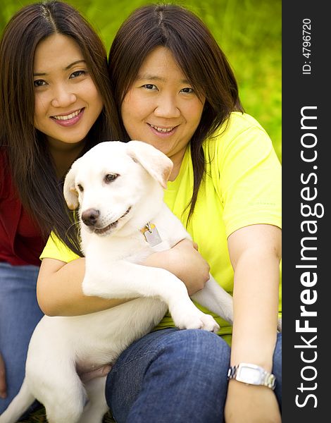 Two beautiful asian women holding a labrador dog in a park. Two beautiful asian women holding a labrador dog in a park