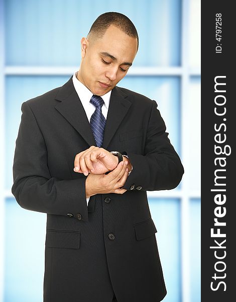 A man in business suit checking his watch in his office. A man in business suit checking his watch in his office