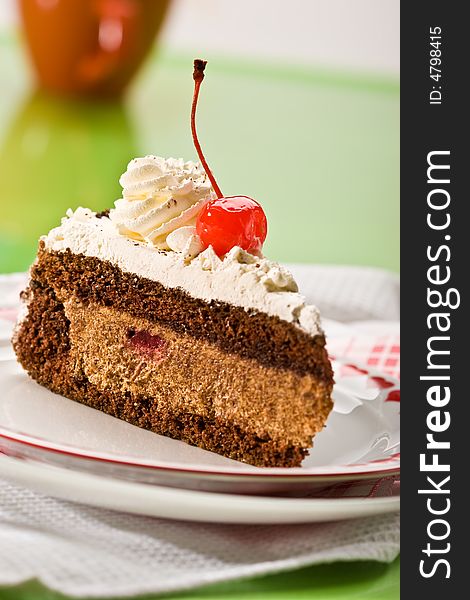 Slice of chocolate cake and cherry on the plate