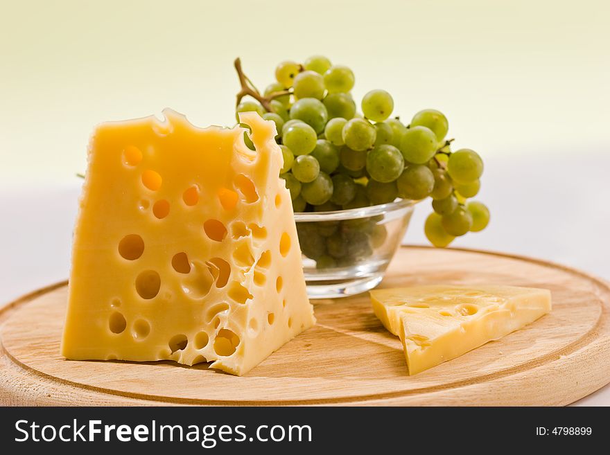Piece of cheese on the board and grapes