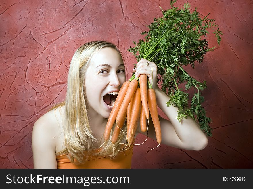 Beautiful woman with carrots against the red background. Beautiful woman with carrots against the red background