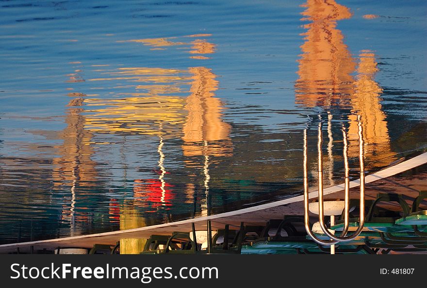 Reflections of sun umbrellas in a pool, waiting people at the beach. Shot at dawn. Conceptual shot for end of spring, start of the summer season. Can work well for end of season too. Reflections of sun umbrellas in a pool, waiting people at the beach. Shot at dawn. Conceptual shot for end of spring, start of the summer season. Can work well for end of season too.