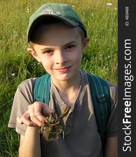 A boy holding the crowfish in the hand at evening lighting. A boy holding the crowfish in the hand at evening lighting