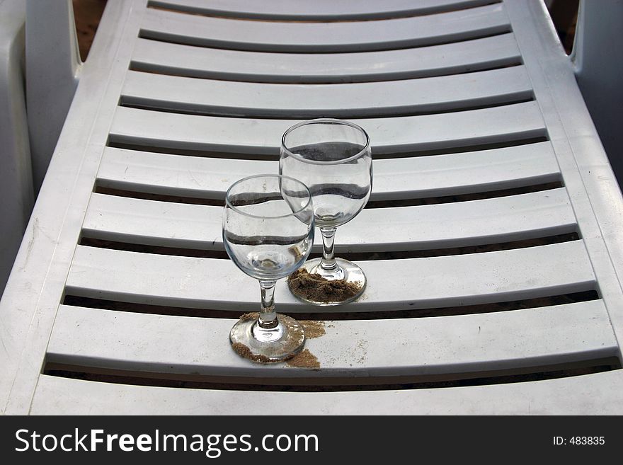 Two empty glasses on the beach chair. Two empty glasses on the beach chair.