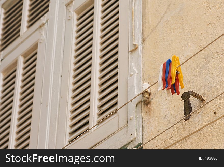 Clothesline and Clothespins on the outside of a building- shutters in the background