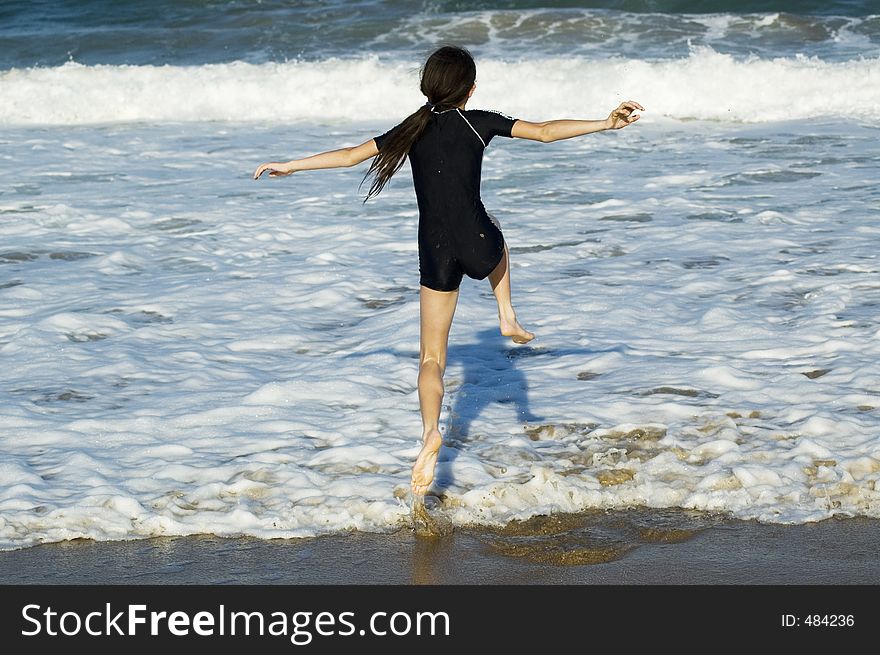 Young girl jumping over the waves rolling in on the beach. Young girl jumping over the waves rolling in on the beach