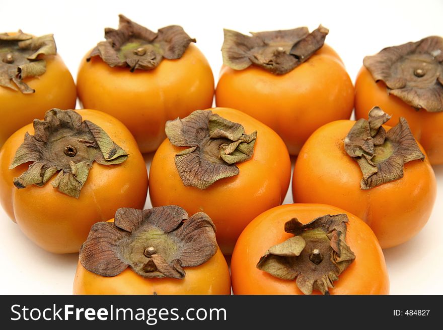 A layout of persimmons arranged in a triangle on a white surface and background