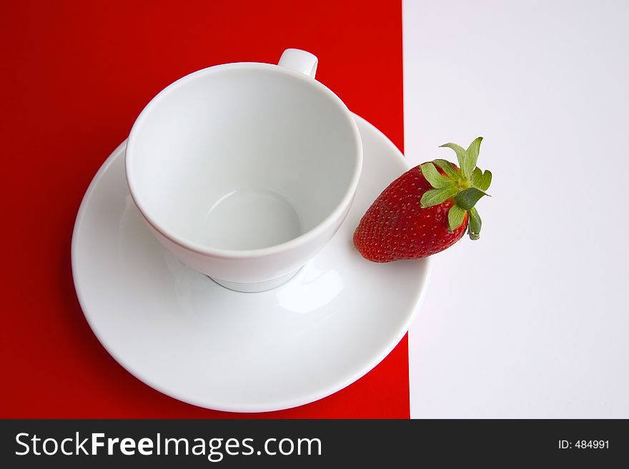 White cup with a red strawberry on a red-white background