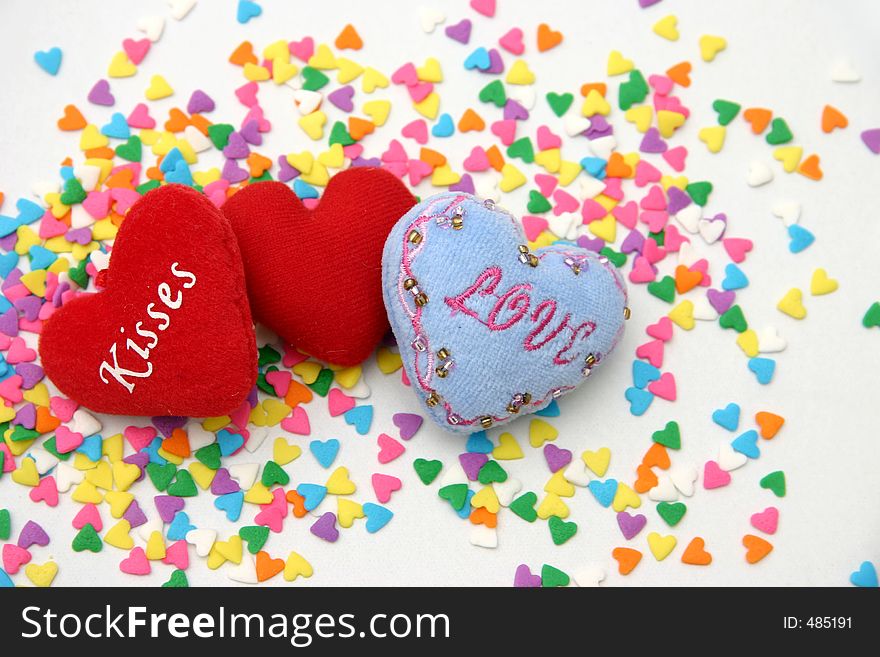 Three small soft spongy cushioned hearts sprinkled with multi colored candied hearts. Three small soft spongy cushioned hearts sprinkled with multi colored candied hearts