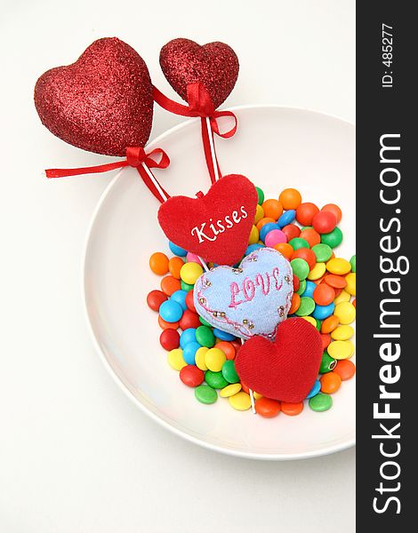 Glitter coated hearts, heart-shaped cushions and multi colored sweets on plate. Glitter coated hearts, heart-shaped cushions and multi colored sweets on plate