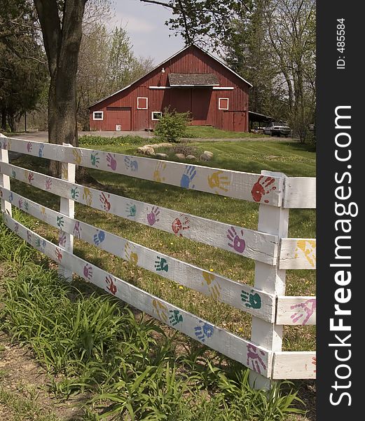 Colorful Hand prints on a white fence- barn in background