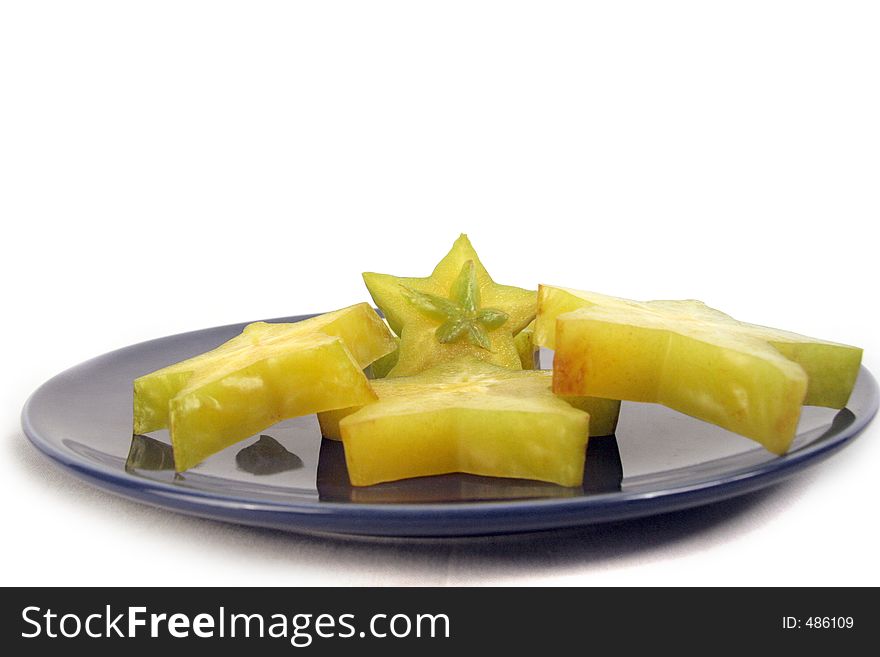 Pieces of starfruit organized neatly on a blue ceramic plate. Pieces of starfruit organized neatly on a blue ceramic plate