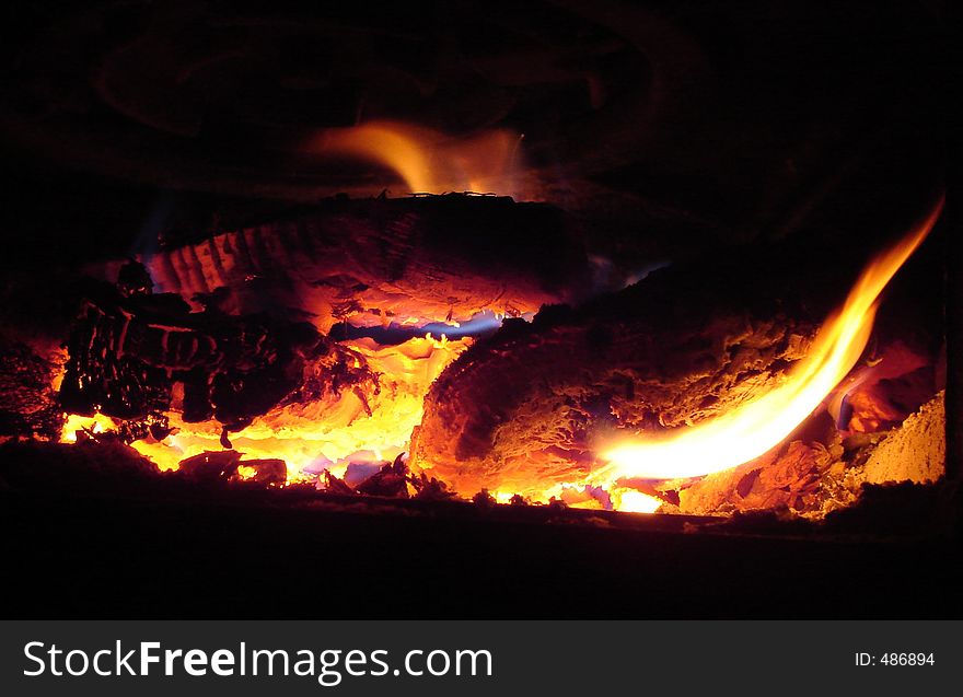 Woods burning in a stove. Beautiful flames and colors. Copy space in black areas. Woods burning in a stove. Beautiful flames and colors. Copy space in black areas.