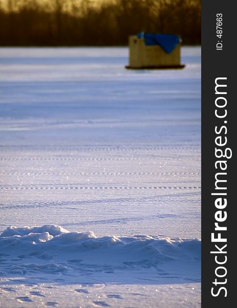 Ice house sits on frozen lake at dawn - focus on foreground. Ice house sits on frozen lake at dawn - focus on foreground