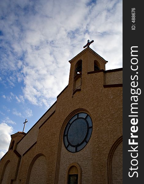 A vertical shot of a brick church against a sky decorated with cloud.