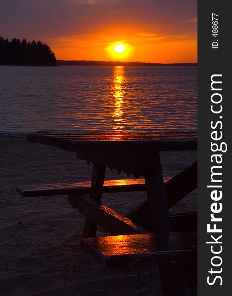 A picnic table lit with late day run rays on a beach at Astotin Lake, Elk Island National Park, Alberta, Canada. A picnic table lit with late day run rays on a beach at Astotin Lake, Elk Island National Park, Alberta, Canada.