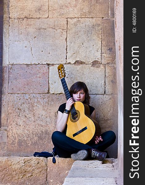 Young guitar performer against brickwall