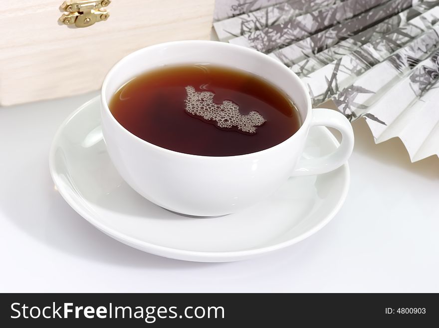 A cup of tea with fan and wooden box on bright background. A cup of tea with fan and wooden box on bright background