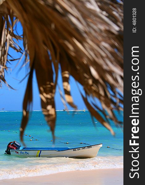 View of a boat in the Caribbean from the position of an island hut. View of a boat in the Caribbean from the position of an island hut.