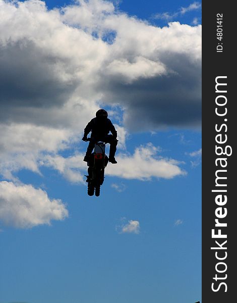 Stunt biker mid-jump with sky background.