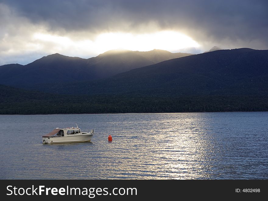 A boat moored in New Zealand floating on the reflecting waters. A boat moored in New Zealand floating on the reflecting waters.