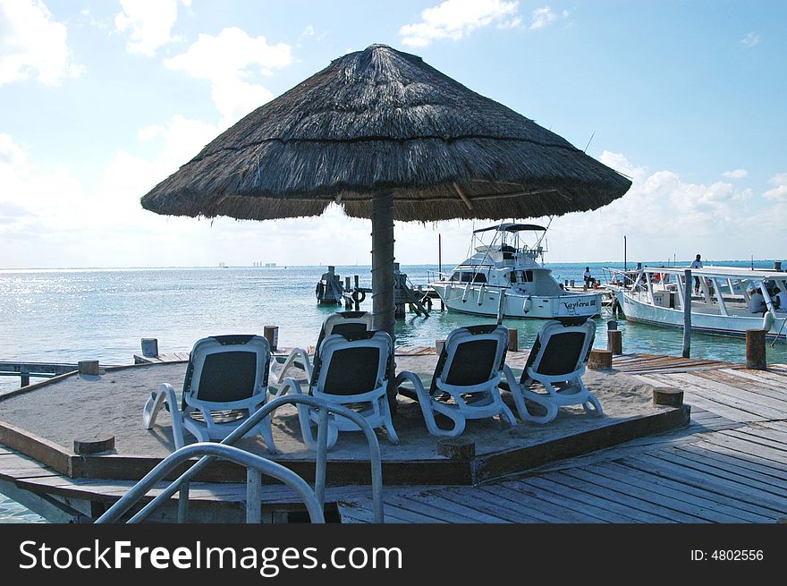 A view of ocean ,beach ,umbrellas,wharf wood and boats in beautiful cancun. A view of ocean ,beach ,umbrellas,wharf wood and boats in beautiful cancun