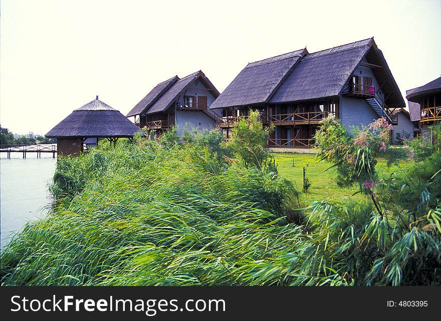 Resort village houses next to a grassy field along a river. Resort village houses next to a grassy field along a river.