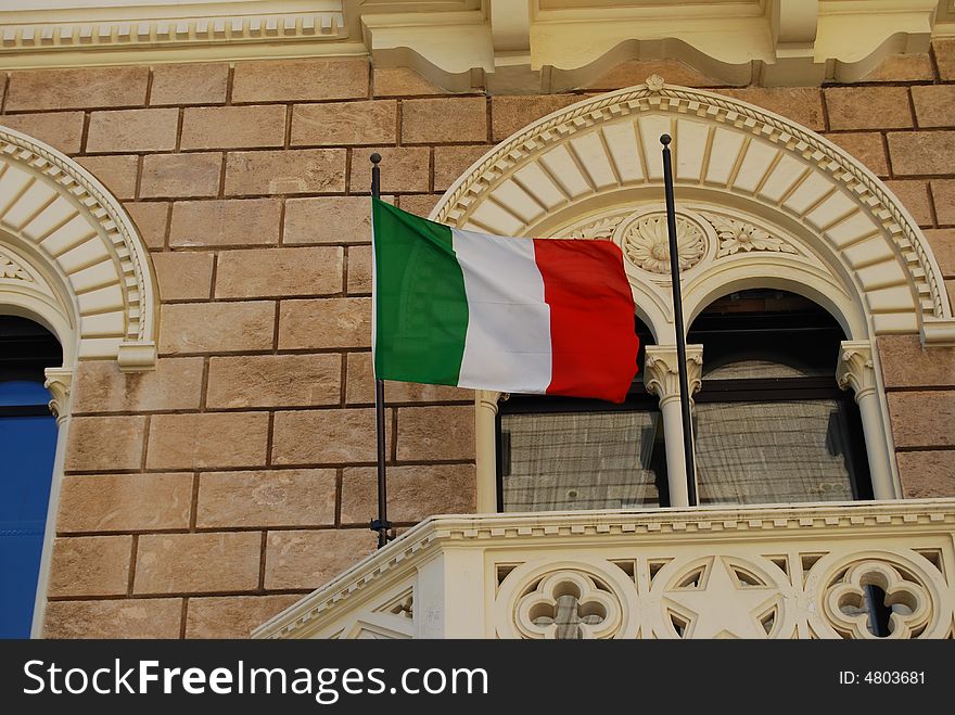 Ornamental balcony with flags of Italy on a brown wall