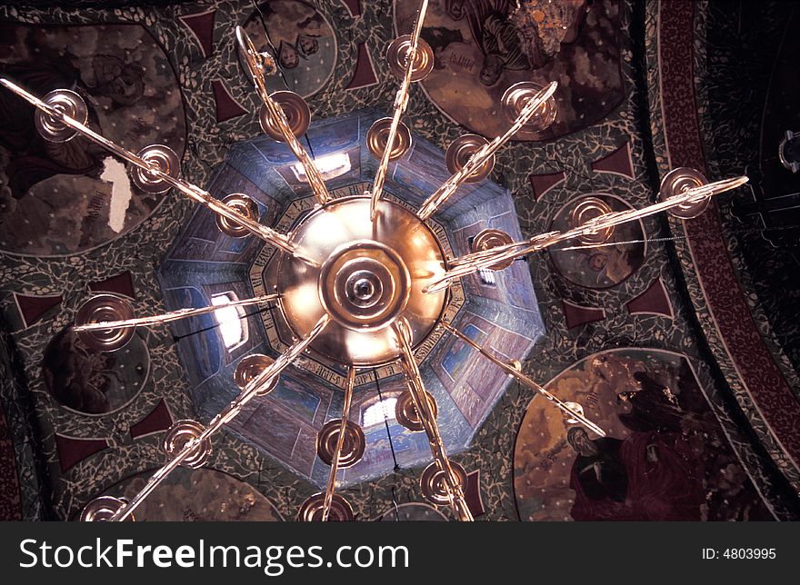 A view from below a golden chandelier in a church.