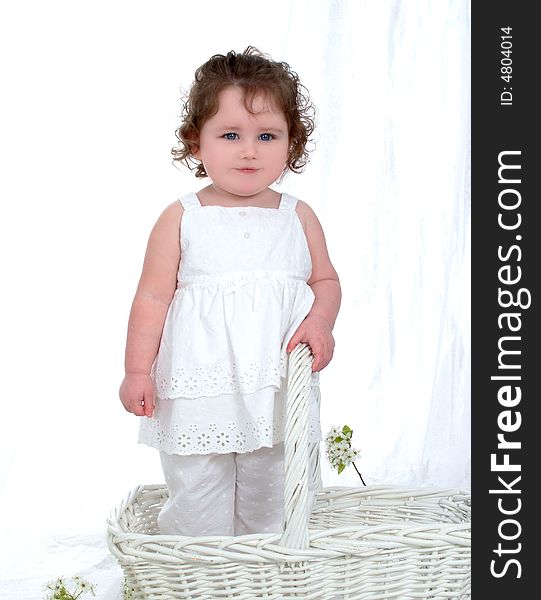 Baby girl in wicker basket in front of white background with flowers on floor and chick perched on flowers. Baby girl in wicker basket in front of white background with flowers on floor and chick perched on flowers