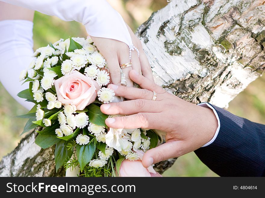 Two hands of bride and groom over a wedding bouquet. Two hands of bride and groom over a wedding bouquet