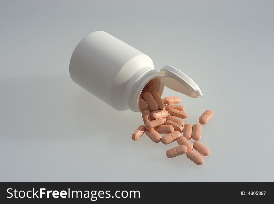 Medicine pills with a white bottle on a grey background. Close-up