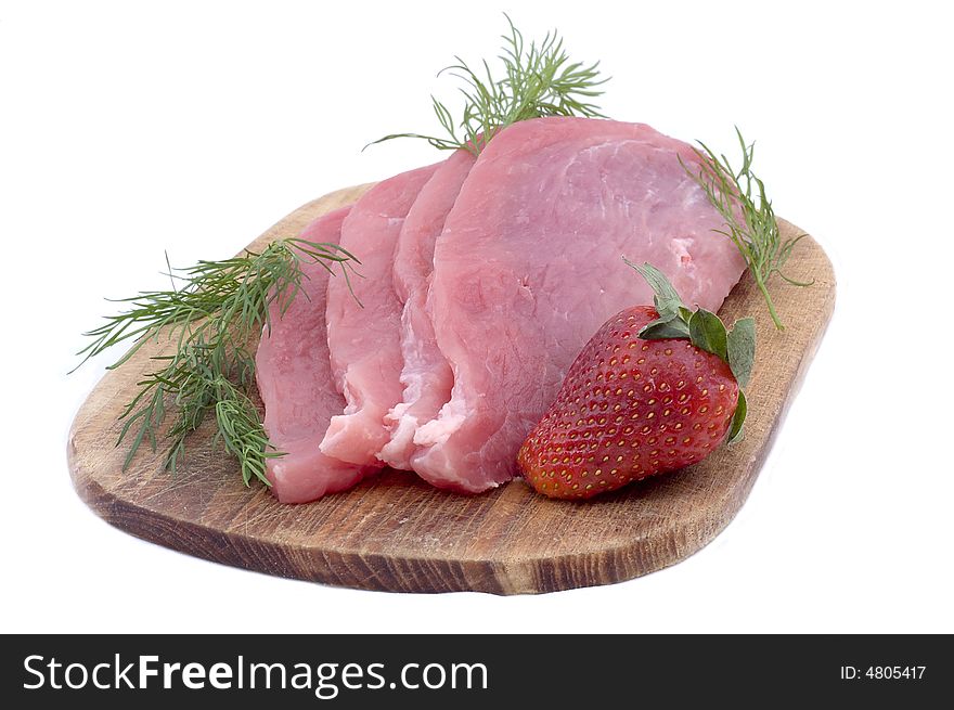 Raw pork schnitzel with dill and a strawberry on a wooden hardboard isolated on white