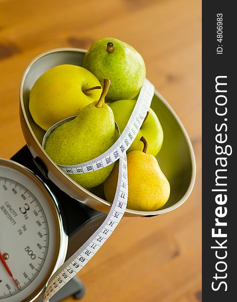 Apple and pear on kitchen scales with tape measure. Apple and pear on kitchen scales with tape measure