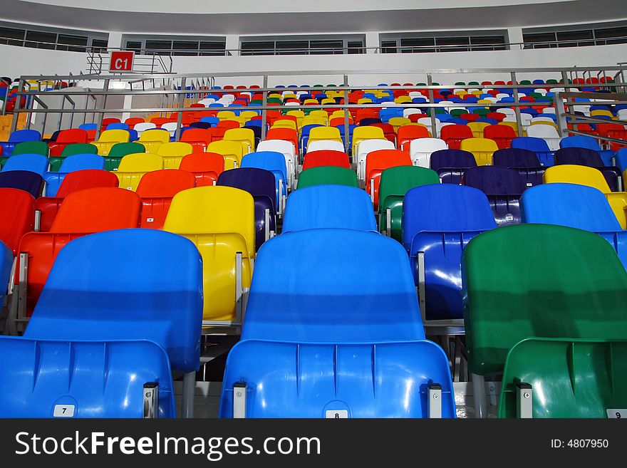 Several rows of multi-coloured plastic stadium seats