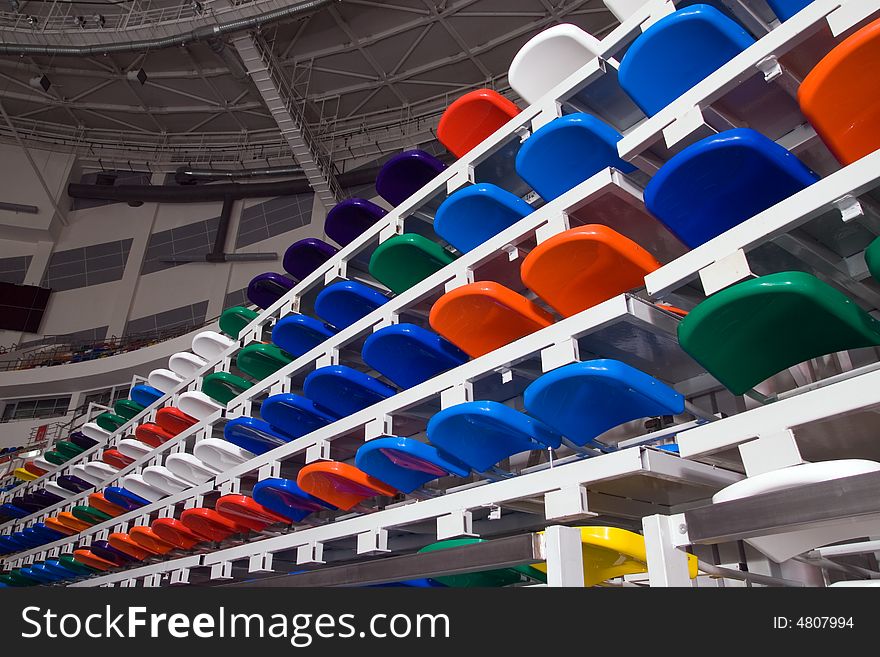 Several rows of multi-coloured plastic stadium seats