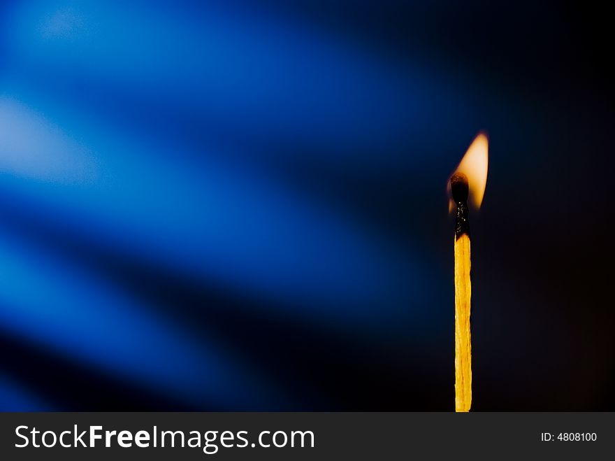 Flame of matchstick against blue background