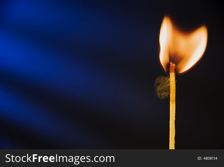 Flame of matchstick against blue background