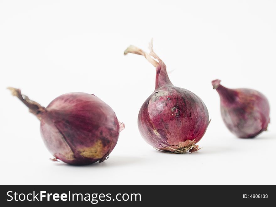 Three red onions on white background, shallow DOF