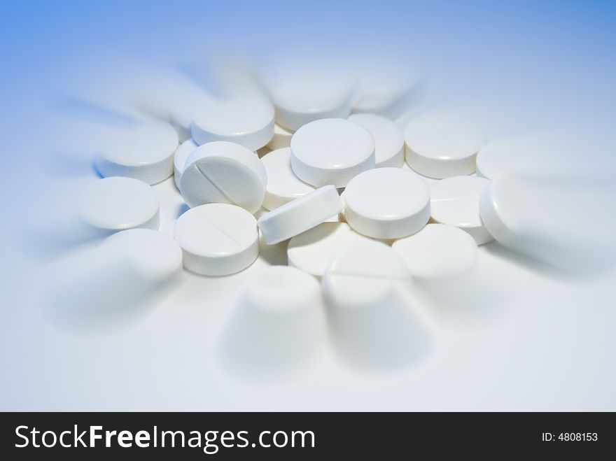 Close-up shot of white pills on white background