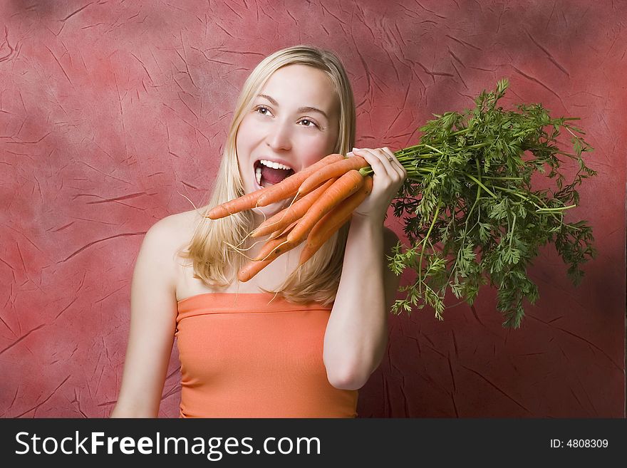 Beautiful woman with carrots against the red background. Beautiful woman with carrots against the red background