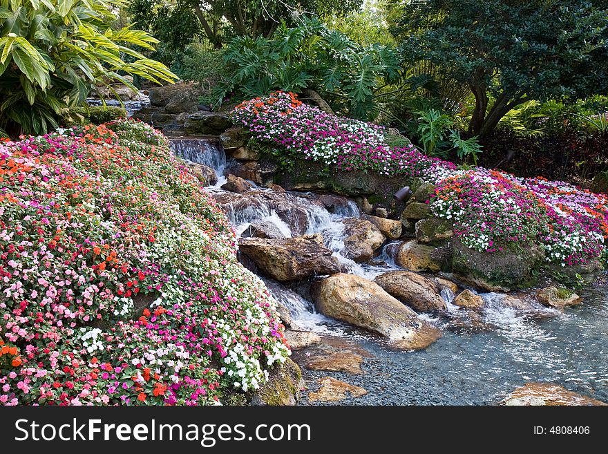Small waterfall surrounded by colorful flowers