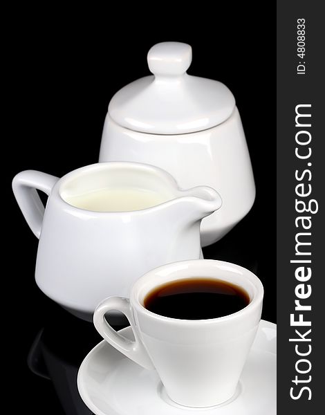 Cup of coffee, sugar and milk pot over black background