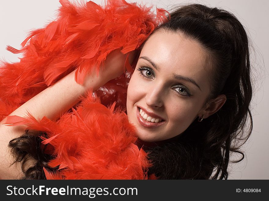 The beautiful girl in a red boa on grey background