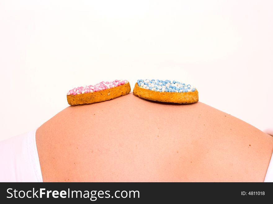 A biscuit with blue and pink candy on pregnant stomach. What will it be?